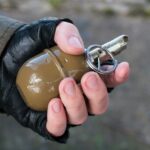 Grenade in a hand in cutted gloves on ruined back